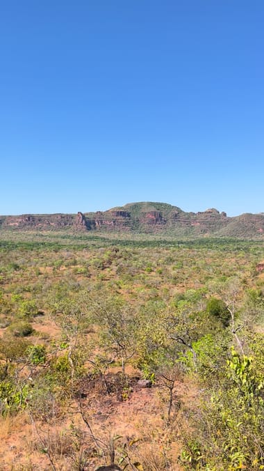 Mulher de chapéu olhando o cerrado e as mesas do alto da serra